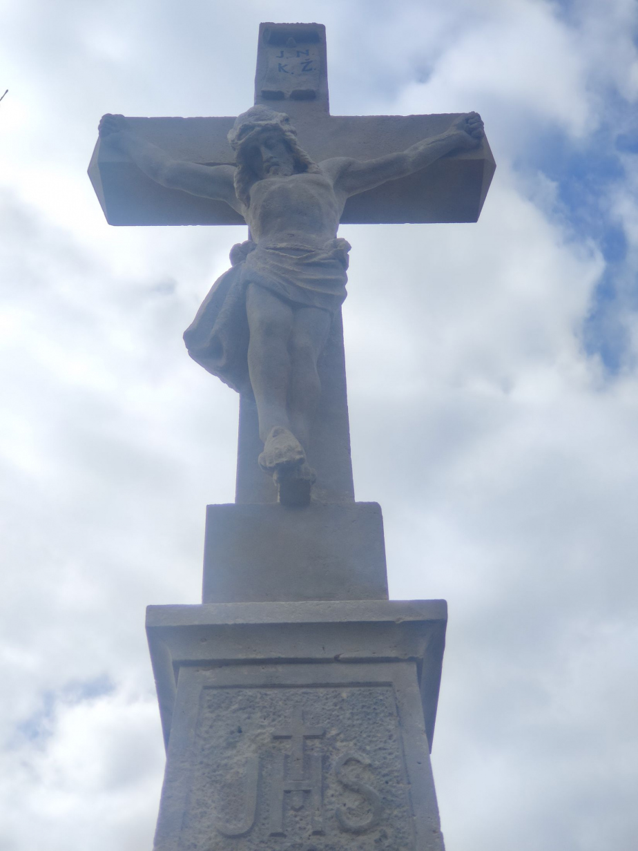 Detail vrcholového kříže s ukřižovaným Ježíšem Kristem. 