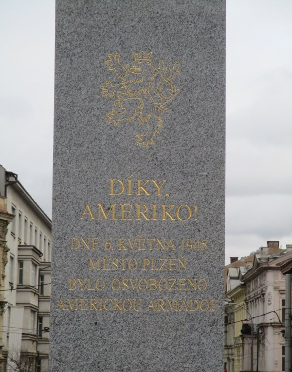 Detail nápisu. Po roce 1990 proběhla architektonická soutěž na podobu pomníku. Vítězný návrh byl pro své pojetí odmítnut, a tak byl vytvořen nový, který pracoval se dvěma monumentálními pylony s oboustranně umístěnými nápisy. 