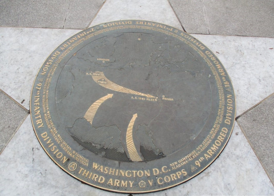Detail pomníku. Kruhová deska znázorňuje v nízkém reliéfu mapu Evropy a hlavní směry postupu jednotek americké armády s jejich označením. 
