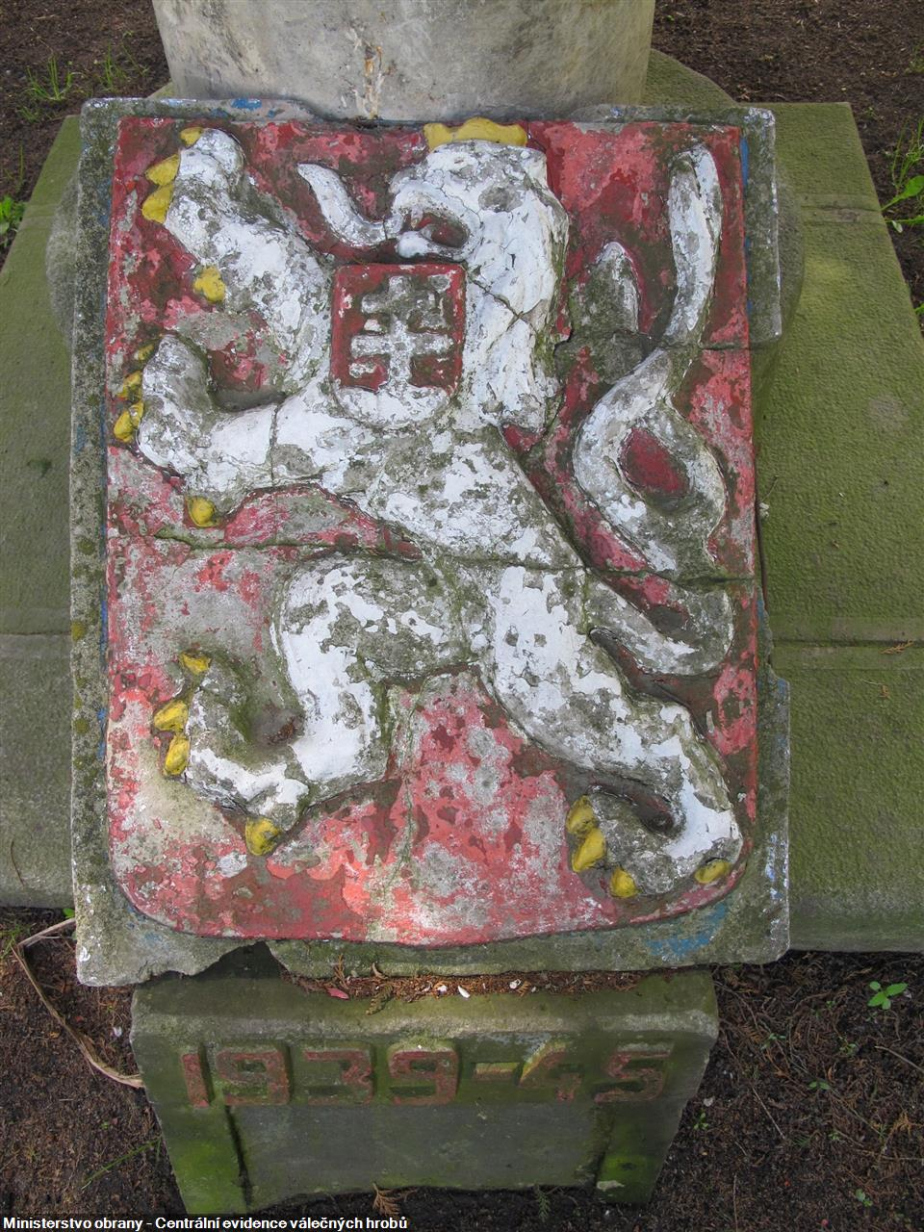 Detail původního poškozeného malého znaku u paty pomníku. 